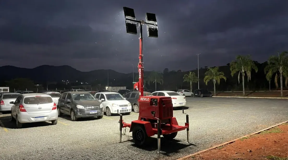 Torre de iluminação iluminando um estacionamento cheio à noite